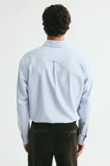 Camisa de algodón H&M Oxford con estampado de rayas verticales celestes y blancas, cuello americano, bolsillo en el pecho y manga larga.