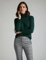 Polera de tejido fino, color rosado, con cuello alto, manga larga y detalle de tajo en los puños.