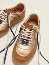 Championes urbanos de cuero en tonos tostado y marrón claro, con detalles en rojo, cordones bicolor, suela de goma y el número 1986 bordado en el talón.