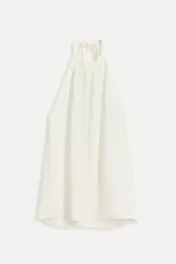 Top blanco de viscosa con cuello halter ajustable con lazadas y espalda descubierta.