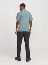 Polo de hombre confeccionado en tejido piqué de algodón, con cuello clásico, cierre frontal de botones y manga corta. Presenta un diseño liso en color azul grisáceo con un pequeño detalle bordado en el pecho.