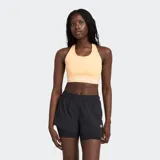 Sostén deportivo de sujeción media, color melocotón/naranja claro, con cuello halter y banda elástica inferior con el logo de New Balance.