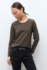Remera de manga larga color verde oliva, con cuello redondo y detalle de botones metálicos en los puños.
