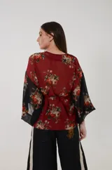 Kimono de gasa con motivos florales, que combina tonos bordó y negro en el cuerpo y las mangas. Presenta mangas anchas cuadradas y faja ancha tipo lazo para atar en la cintura.