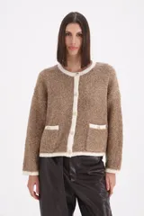 Saco tipo cardigan de tejido bouclé en color visón, con bordes y detalles en color crema. Presenta cuello redondo, cierre frontal con botones y dos bolsillos delanteros con solapa.