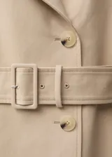 Trench coat de corte recto y diseño largo en color beige. Presenta cierre de doble botonadura, cuello con solapas de muesca, trabillas en los hombros y en los puños, y cinturón desmontable con hebilla a juego. Incluye dos bolsillos laterales y abertura posterior en el bajo.
