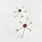 Aros plateados con forma de estrella de mar con un cristal en el centro y bolitas en las puntas.