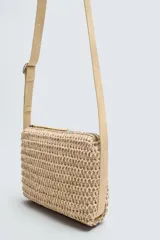 Bandolera color beige con acabado trenzado, compartimento principal con cierre de cremallera, bolsillo plano interior y asa de hombro ajustable.