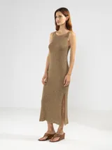 Vestido midi sin mangas, confeccionado en punto jersey con hilo Lurex que aporta un brillo sutil. Presenta escote bote redondeado y aberturas laterales en el ruedo.