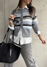 Saco tipo cardigan de punto con diseño de rayas horizontales en tonos gris, azul y blanco. Presenta cuello redondo, cierre frontal con botones y mangas largas.