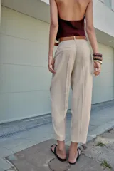 Pantalón tobillero azul marino de tiro medio, con pinzas delanteras, bolsillos frontales, falsos bolsillos con solapa en la espalda y cierre frontal con cremallera, botón y gancho. Incluye cinturón de cuero sintético tostado con hebilla metálica dorada.