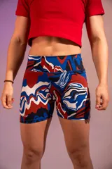 Calza corta deportiva con tiro alto y estampado abstracto en tonos rojo, azul, blanco y negro.