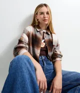 Camisa de manga larga confeccionada en franela de viscosa, con estampado de cuadros en tonos marrones, beige y gris. Presenta cuello clásico, cierre frontal con botones y bolsillo en el pecho.