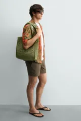 Bolso tipo shopper de color naranja con acabado trenzado y diseño estructurado. Cuenta con compartimento principal y dos asas cortas de mano.