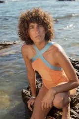 Malla enteriza color naranja con tiras cruzadas en el cuello de color celeste.