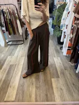 Pantalón ancho de lino color tostado, con cintura elástica y detalles de bordado rojo a lo largo de las piernas.