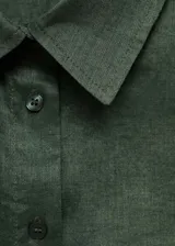 Camisa de corte recto color verde militar, con cuello camisero, cierre frontal de botones, manga larga abotonada y un bolsillo de parche en el pecho.