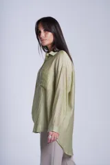 Camisa negra de tela traslúcida con cuello clásico, cierre frontal con botones y dos bolsillos de parche en el pecho.