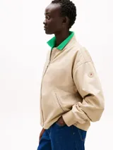 Campera bomber color beige, acolchada y repelente al agua, con cuello de béisbol, cierre frontal, puños y cuello de punto canalé, y dos bolsillos laterales ribeteados en diagonal.