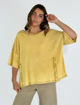 Remera amarilla de corte holgado con mangas cortas y detalle de botones en los laterales.