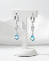 Caravanas colgantes de plata 925 con diseño de doble gota, una superior con pavé de circonias blancas y una inferior con una circonia central color celeste.