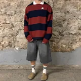 Buzo tipo polo de corte oversize, con diseño de rayas horizontales anchas en color bordó y azul marino. Presenta cuello polo blanco y un pequeño logo bordado en el pecho.