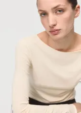 Camiseta entallada de color beige, con cuello barco y manga larga.