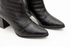 Botín de cuero negro con textura croco, punta fina y taco cuadrado de 6 cm.