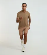 Bermuda deportiva color beige, confeccionada en poliéster, con cintura elástica y cordón de ajuste. Presenta bolsillos laterales y costuras contrastantes.