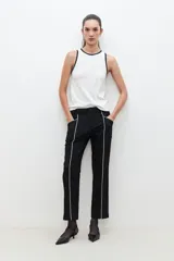 Pantalón negro de corte recto con vivo blanco en los laterales.
