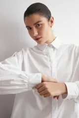Camisa de corte oversized, color blanco, con cuello clásico, cierre frontal de botones y mangas largas.