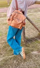 Mochila marrón de cuero con efecto gastado, múltiples bolsillos con cierre y correas ajustables.