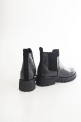 Botas Chelsea negras de cuero con elástico lateral, suela track y tirador trasero.