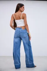 Jean de corte wide leg con tiro medio, confeccionado en denim rígido sin elastano. Presenta un diseño de paneles con costuras verticales y un ruedo con detalle de costura horizontal y terminación desflecada.