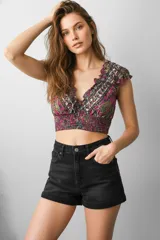 Top corto ajustado al cuerpo, con escote profundo en V y volados en los bordes. Presenta un estampado tipo paisley en tonos fucsia, verde oliva y azul oscuro. El cuerpo tiene frunces horizontales (smock).