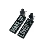 Aros colgantes con forma rectangular con glitter y la leyenda "Make Up" en uno y "Lover" en el otro.