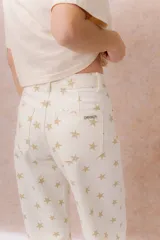 Jean de tiro alto confeccionado en denim color crudo, con estampa de estrellas en tono camel. Presenta calce relajado, pierna recta levemente amplia, costuras verticales delanteras, cinco bolsillos, pasacintos y detalle metálico en la parte posterior.
