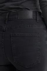 Pantalón de jean azul oscuro, de corte cropped y acampanado, con ruedo desflecado.