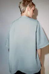 Camisa de manga corta y corte evasé confeccionada en hilatura con mezcla de algodón. Presenta cuello redondo mao y cierre frontal parcial con botones.