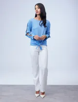 Blusa tejida color celeste con lurex, de manga larga con aberturas y apliques de brillo. Ruedo anudado.