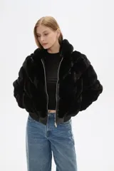 Campera bomber negra de piel sintética con capucha de piel sintética, cierre frontal con cremallera, bolsillos laterales y puños y bajo acanalados.