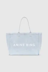 Bolso tipo tote Anine Bing modelo Leo, confeccionado en denim celeste con asas largas y el logo impreso en blanco en el frente.