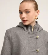 Saco corto negro de polivelour con capucha, cuello alto con cremallera, abotonado delantero cruzado, bolsillos delanteros y mangas largas.