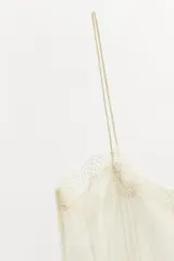 Top semitransparente de viscosa con tejido plisado, escote recto y tirantes finos. Presenta detalles de encaje en el escote y en el ruedo.