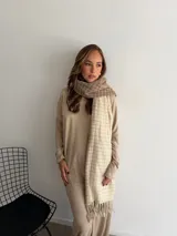 Bufanda de tejido suave con diseño de cuadros grandes en tonos negro y beige, terminada con flecos en los extremos.