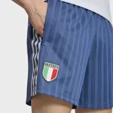 Short Adidas de la selección de Italia, confeccionado en tejido jacquard azul con diseño de rayas verticales. Presenta el escudo de la selección en el frente, las tres tiras características de la marca en los laterales y un corte holgado con cintura ajustable.