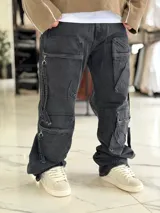 Pantalón cargo de jean negro con efecto acid wash, corte oversize, tiro medio y múltiples bolsillos laterales con solapa y cierres colgantes.