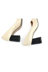 Zapato tipo stiletto color crema con acabado texturizado, punta fina y tacón de bloque en color negro con textura de rejilla.