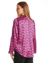 Blusa de satén color fucsia con estampado abstracto en negro, escote en V y mangas largas con presilla y botón para regular el largo.