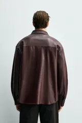 Sobrecamisa relaxed fit de cuero color marrón oscuro, con cuello solapa, manga larga con puño abotonado, bolsillo de parche en el pecho y cierre frontal de botonadura.